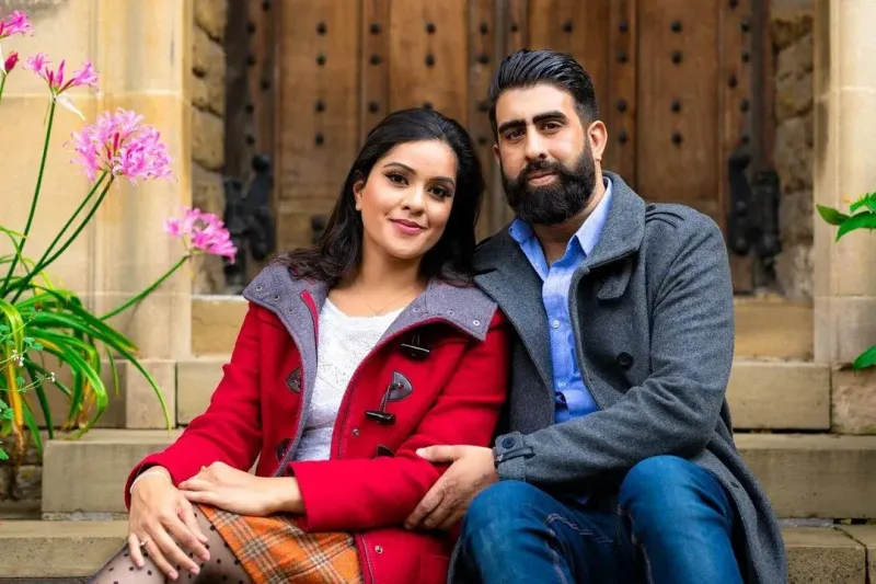 Couple sitting on the stairs of a graden looking happy.