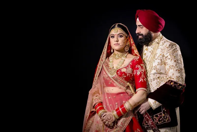 Sikh wedding couple at the Anand Karaj with black background.