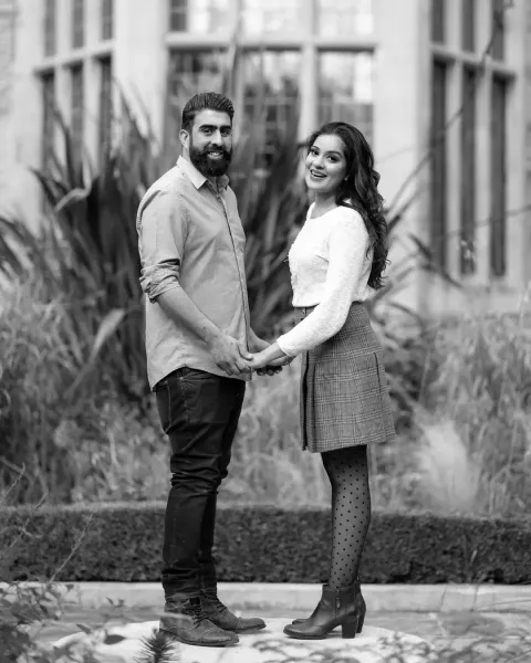 Black and white photoshoot of couple standing in a garden.