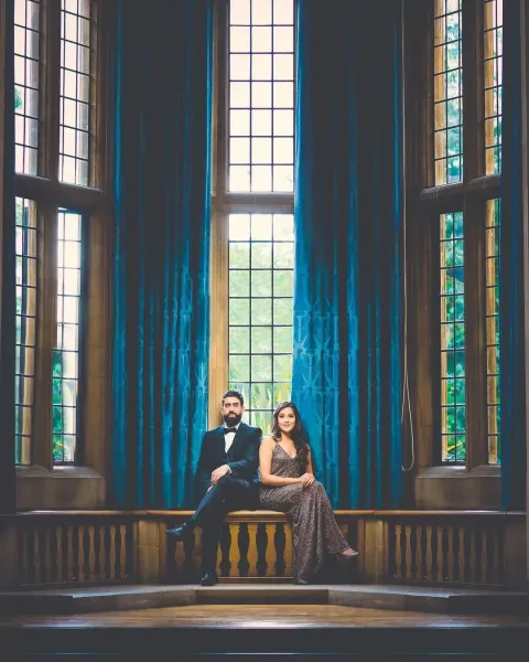 Couple photoshoot with big windows and blue curtain at their back.