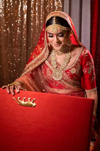 Sikh bride wearing traditional bridal dress opening the gift box at her wedding day.