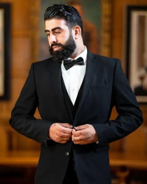 Groom with traditionsl black suit with a bow posing on his reception day.