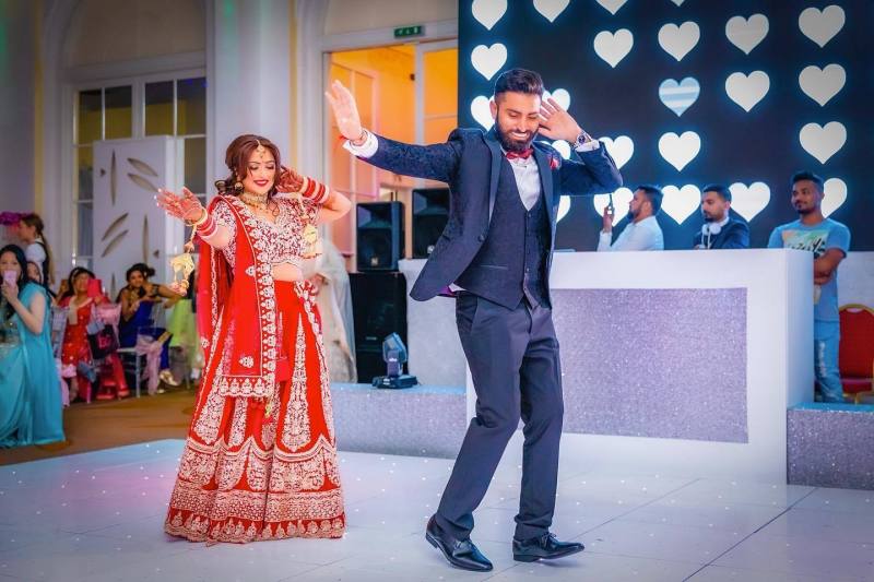 asian-wedding-photography-smiling-bride-and-groom-dance-happily-amidst-festivities