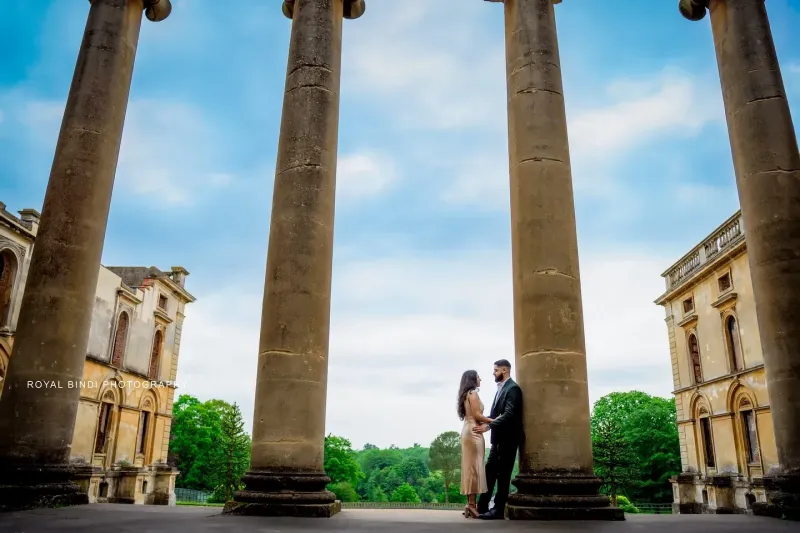 Couple standing with gaint pillars in a historic place.