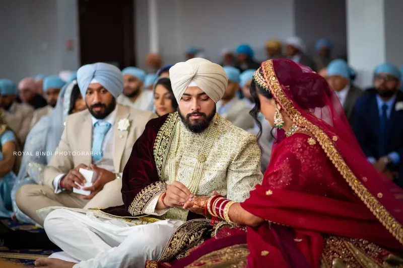 Couple performing Sikh wedding traditions in Gurdwara.