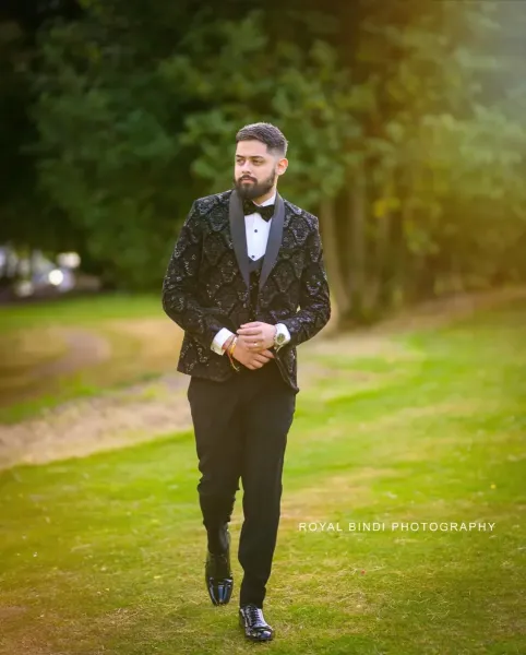 Groom\'s Stunning reception day candid moment in a graden. He is wearing a black three piece suit.