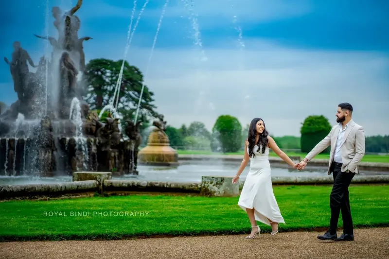 Couple love in front of a gaint fountain in a graden.