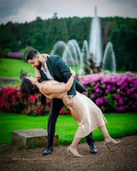 Romantic photography of couple in front of a fountain in a lush green garden.