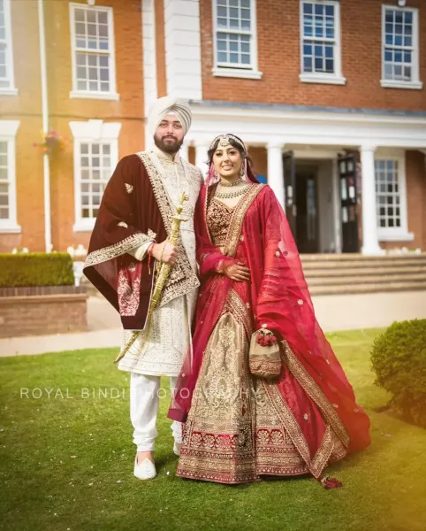 Sikh wedding couple standing in front of a building.