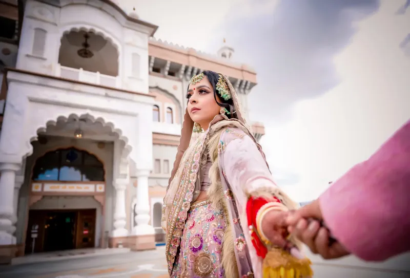 Bride in a wedding dress holding the hand of a man.