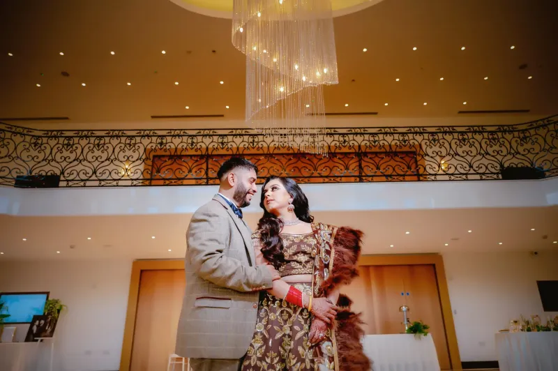 Sikh wedding couple pose under the stunning chandeliers.