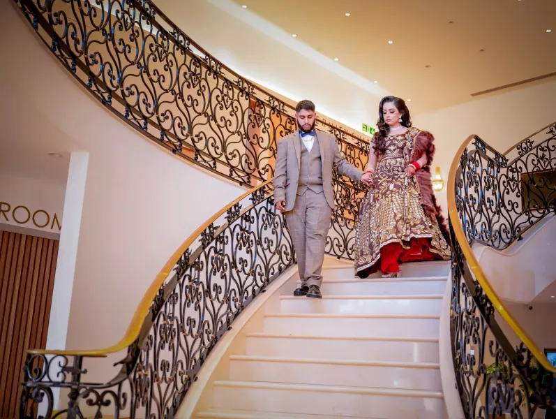 Groom holding the hands of bride coming down from the stairs.