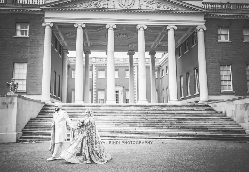 Ramita and Amrits holding their hands passing a historical building.