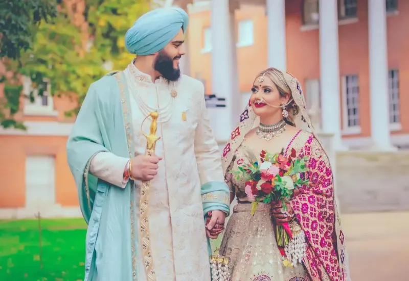 Sikh wedding couple holding the sword and flower in their hands.