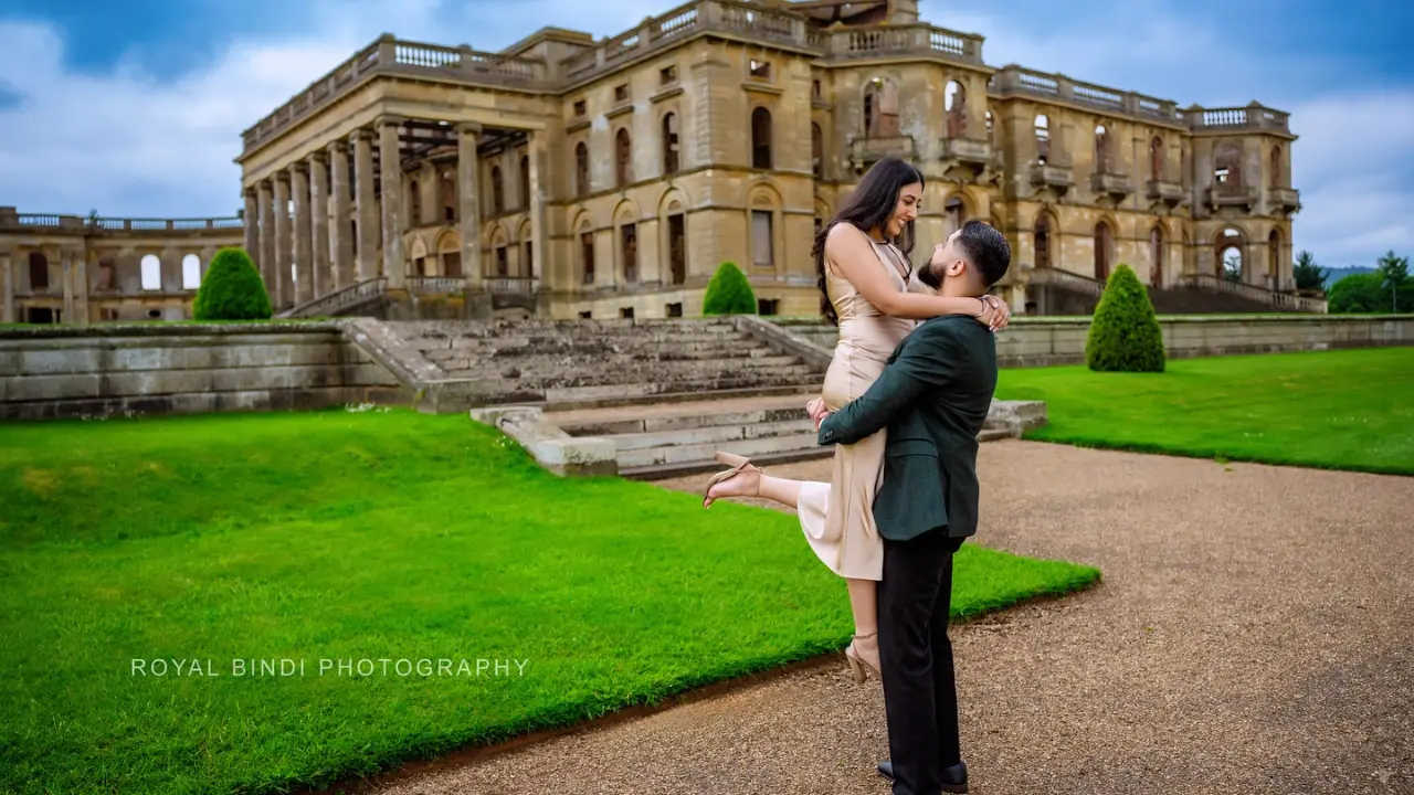 A couple standing in a beautiful location, with the boy lifting the girl in his arms.