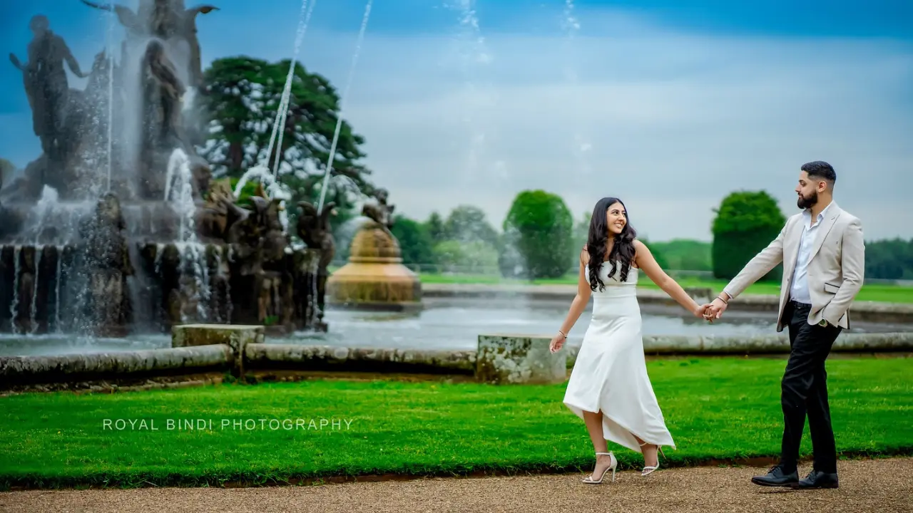 Indian couple walking in a garden with fountain in their background