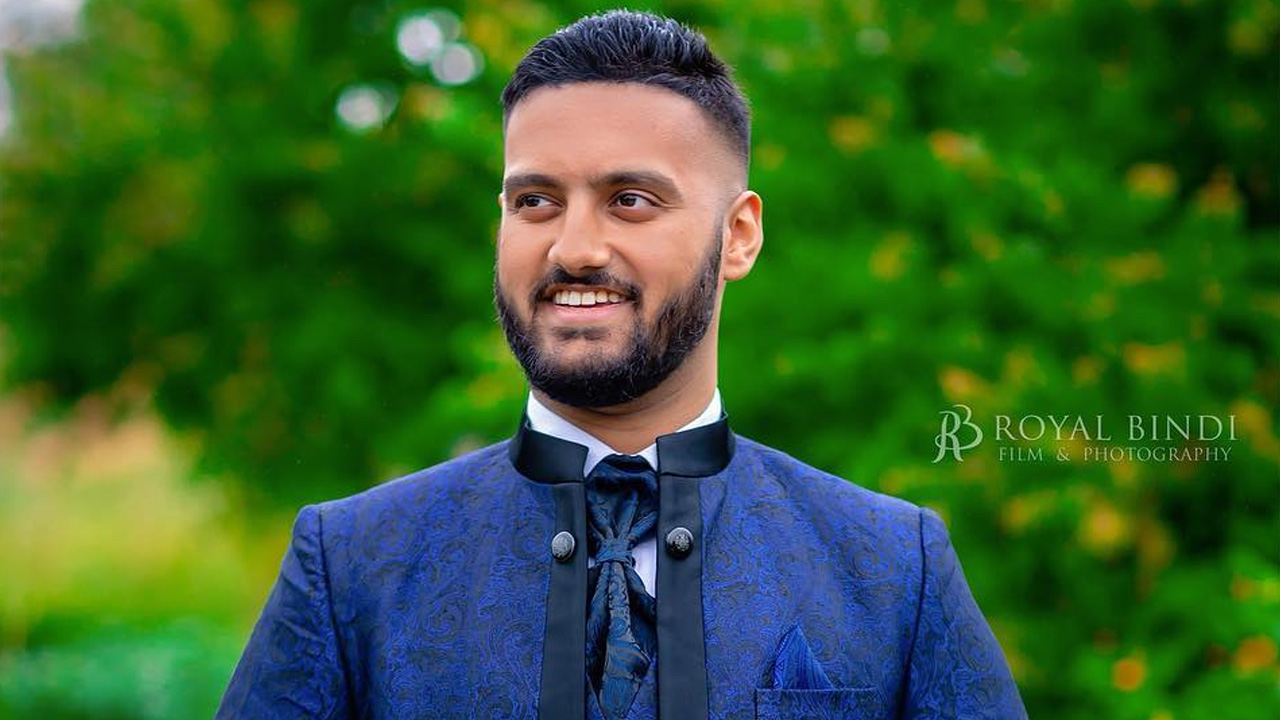 Man in a blue bandhgala suit smiling.