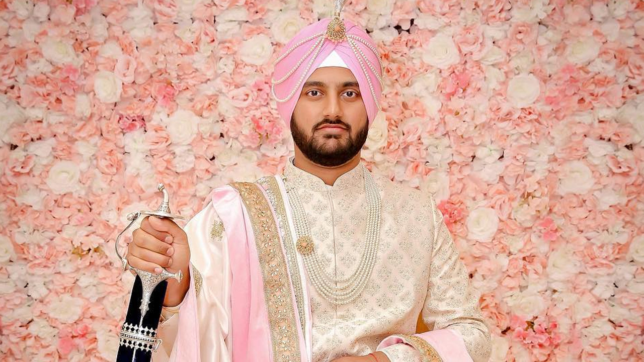 Man in pink and white traditional attire holding a sword