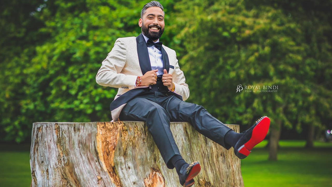 Man in a tuxedo sitting on a tree stump