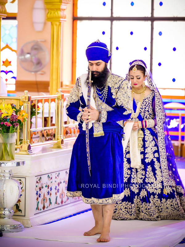 Sikh couple in blue wedding attire during the ceremony.