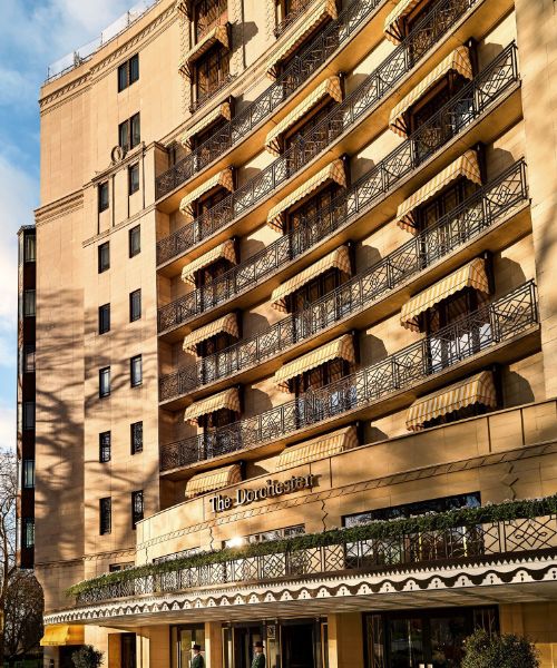 The Dorchester Hotel in London, England. The hotel is a grand building with a curved facade, balconies, and a sign that says "The Dorchester."