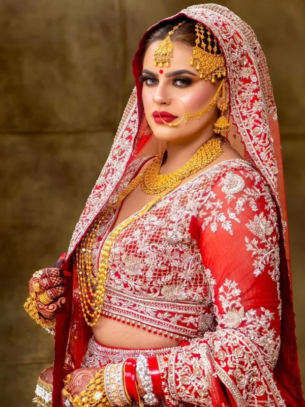 Bride in red lehenga with a gold-embroidered veil