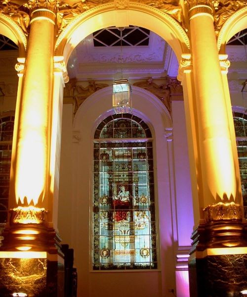 A photo of the interior of a grand building with ornate columns and a stained glass window.