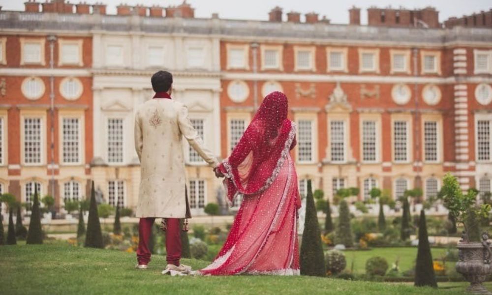 Indian couple standing in front of The Kensington Palace holding hands of each other.