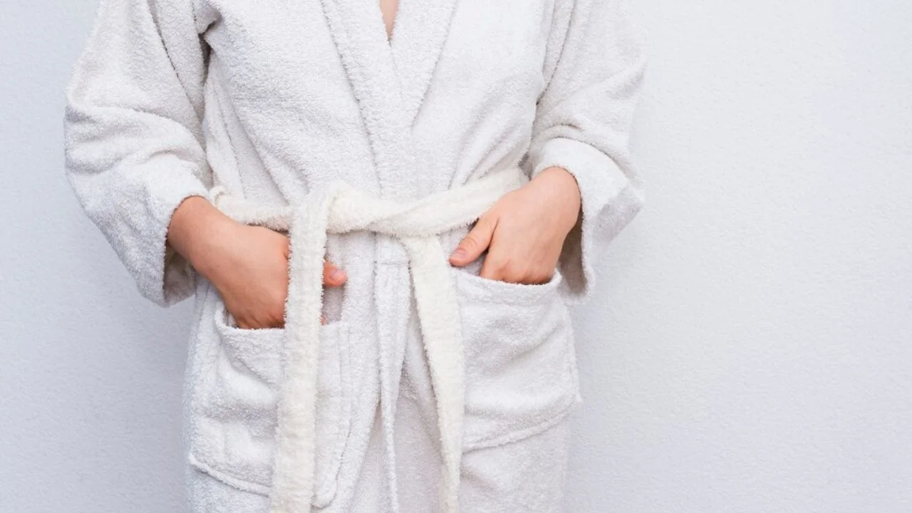 A woman wearing a soft, white bathrobe with her hands in her pockets.