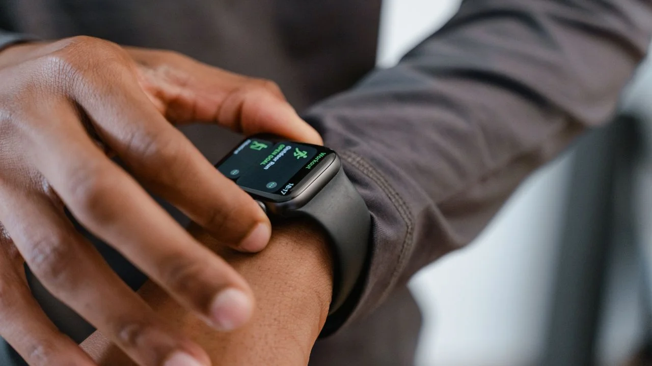 A close-up photo of a person's hand interacting with a fitness watch screen. The screen displays a timer or countdown.