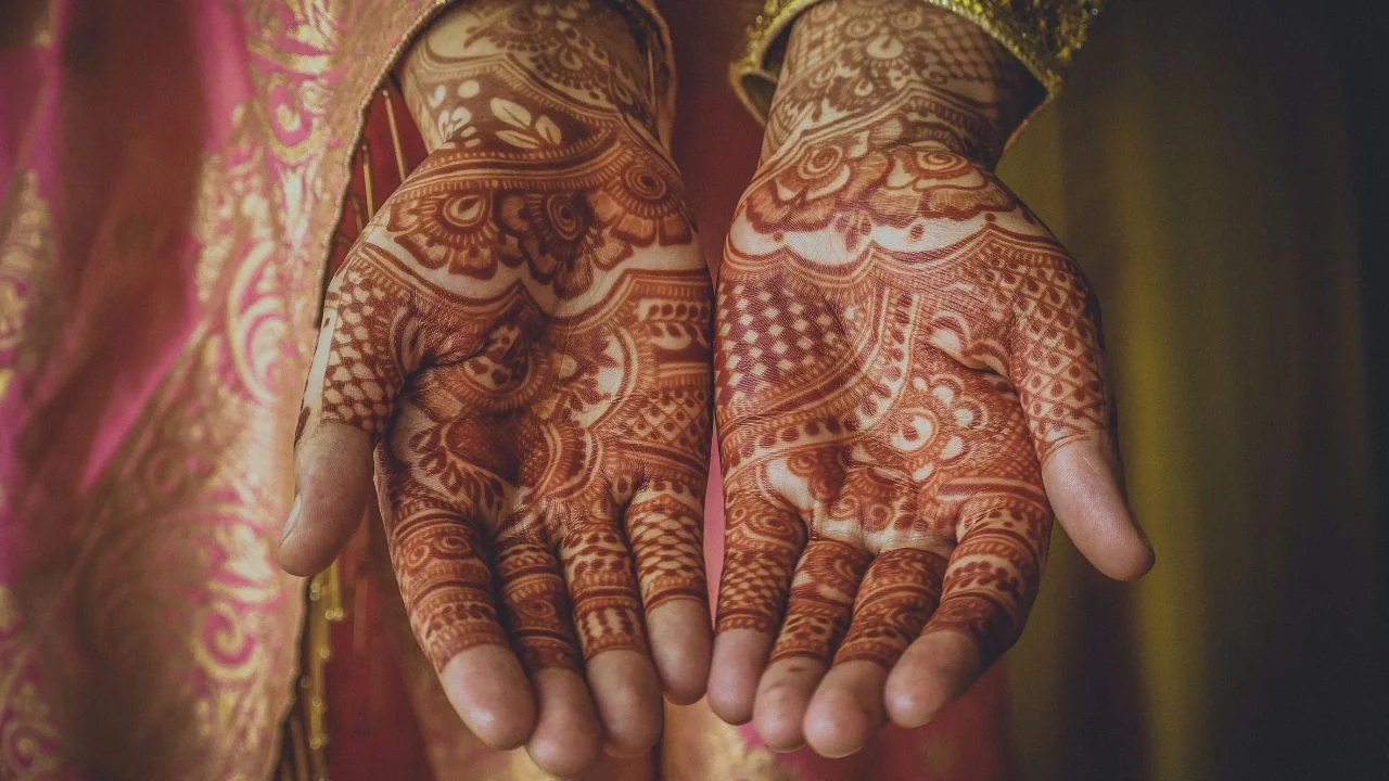 close-up of a woman's hands adorned with floral mehndi designs.