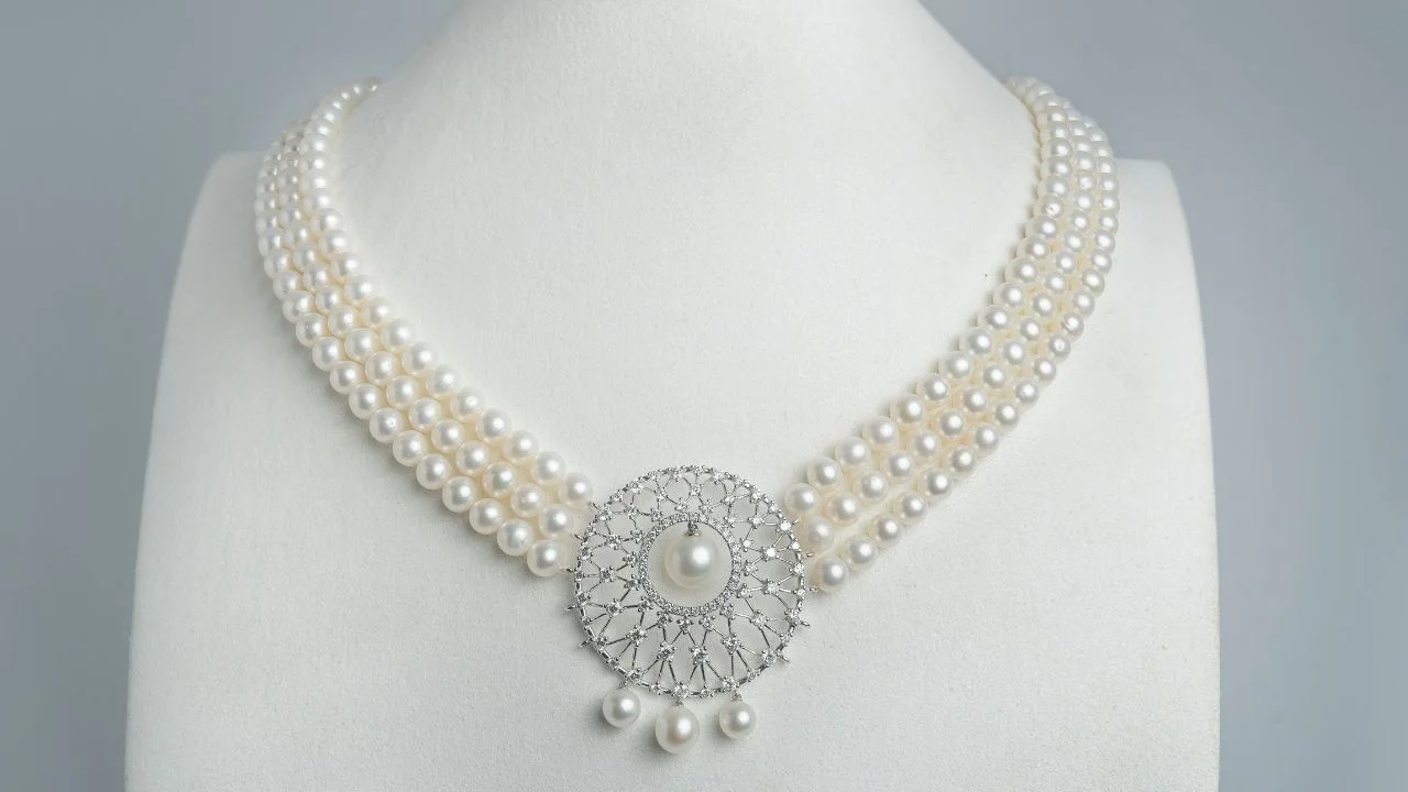 A stunning 3-strand necklace featuring natural white pearls, adorned with a delicate diamond-encrusted pendant.