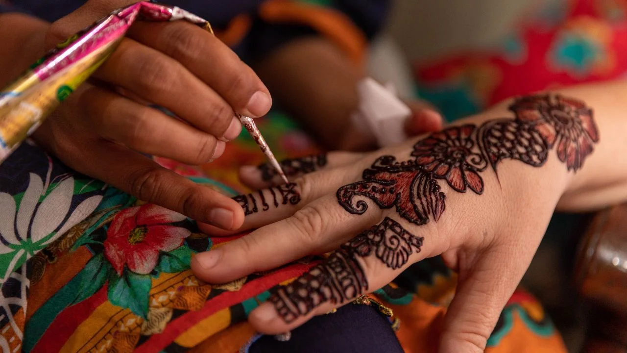 Close-up of a person's hand applying henna to another person's hand.