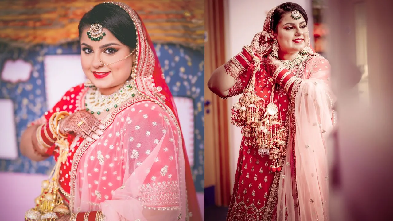 A bride in a red lehenga with gold jewellery smiling and looking at the camera.