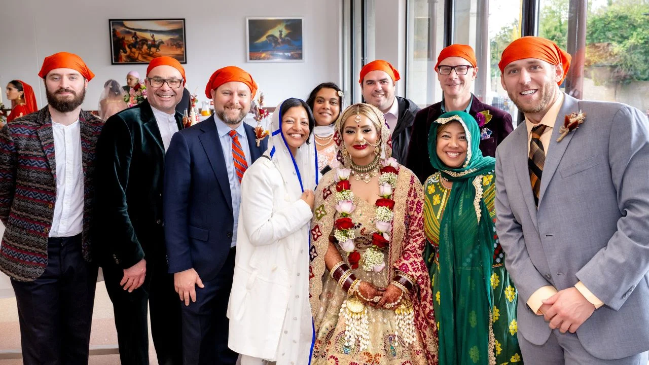 A group of people, including the bride, pose for a wedding photo. Guests wearing traditional Indian wedding clothing.