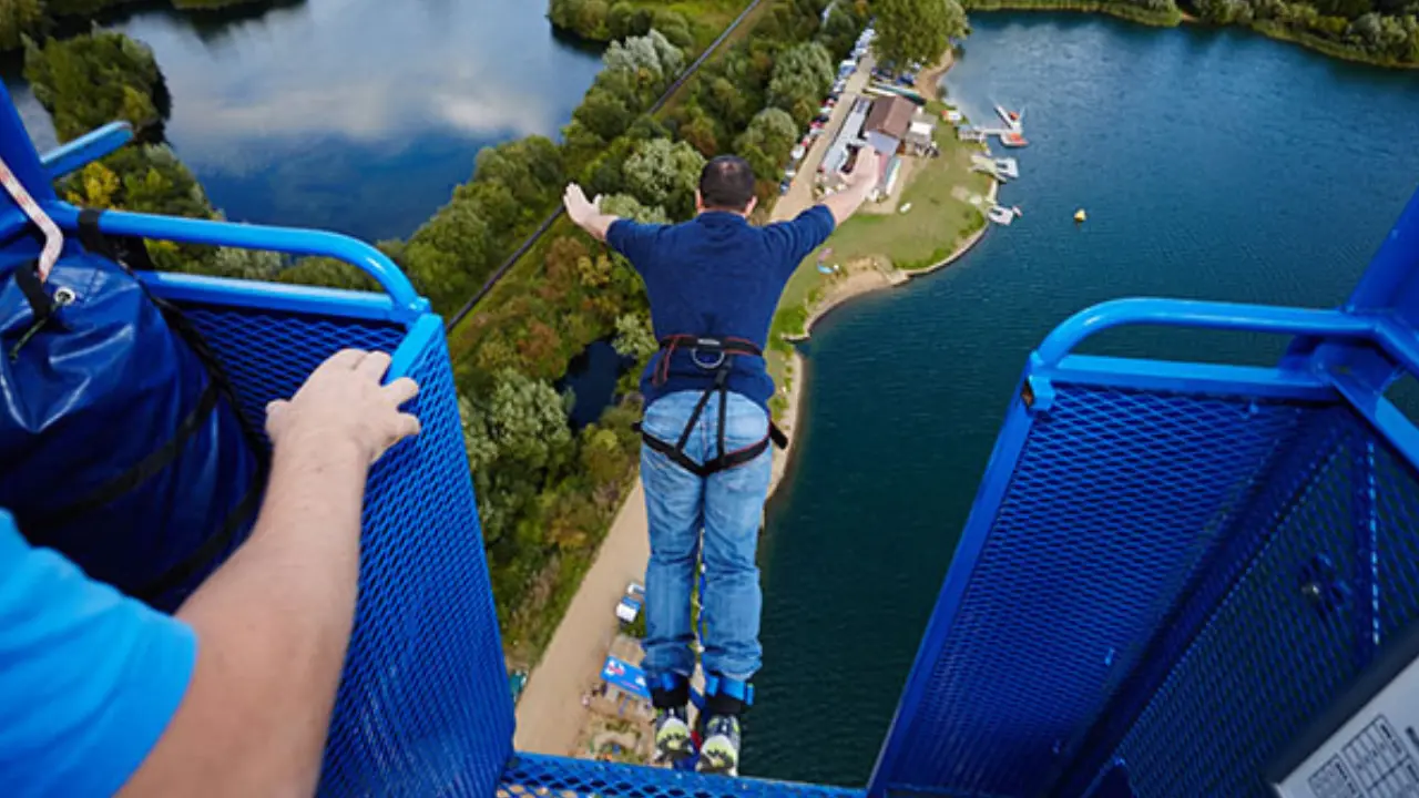 A man bungee jumping from a platform over a lake, symbolizing an adventurous gift experience available through gift vouchers.