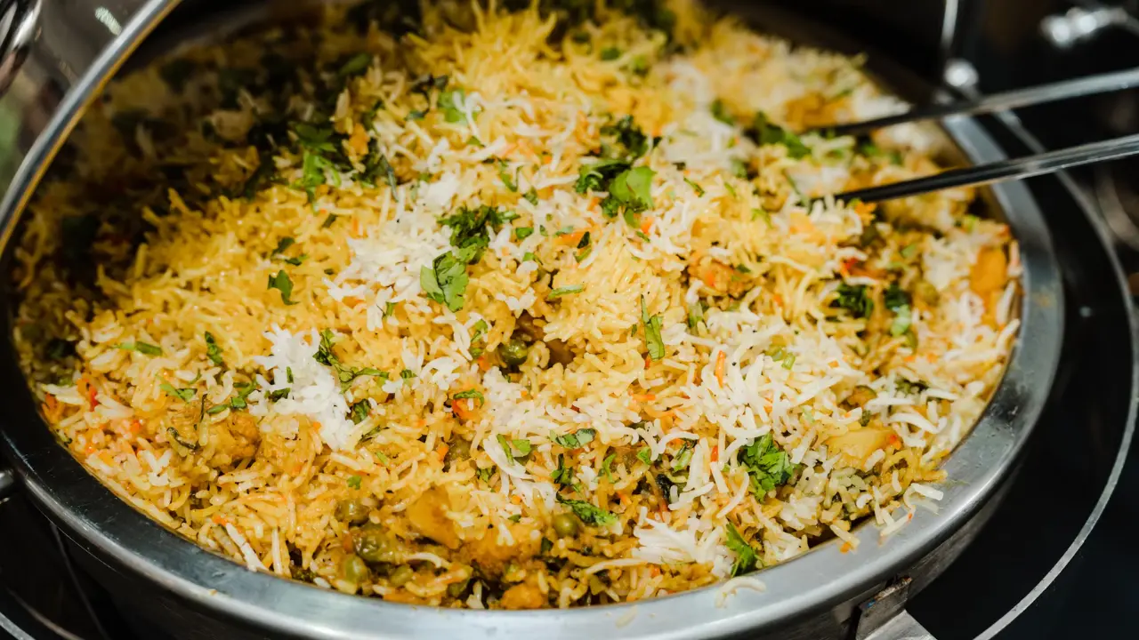 A large bowl of biryani, a flavorful Indian dish, with fragrant spices and garnished with fresh cilantro.