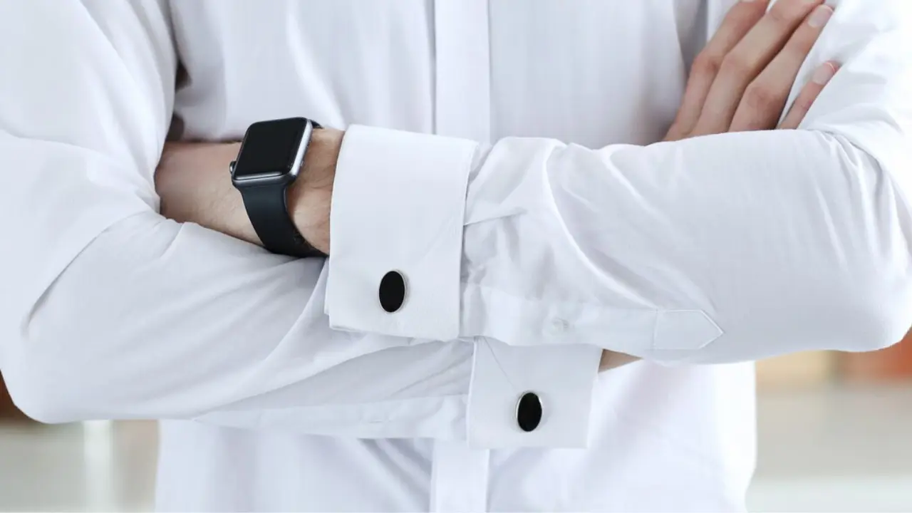 A man with black oval cufflinks and a black smartwatch on his left wrist.