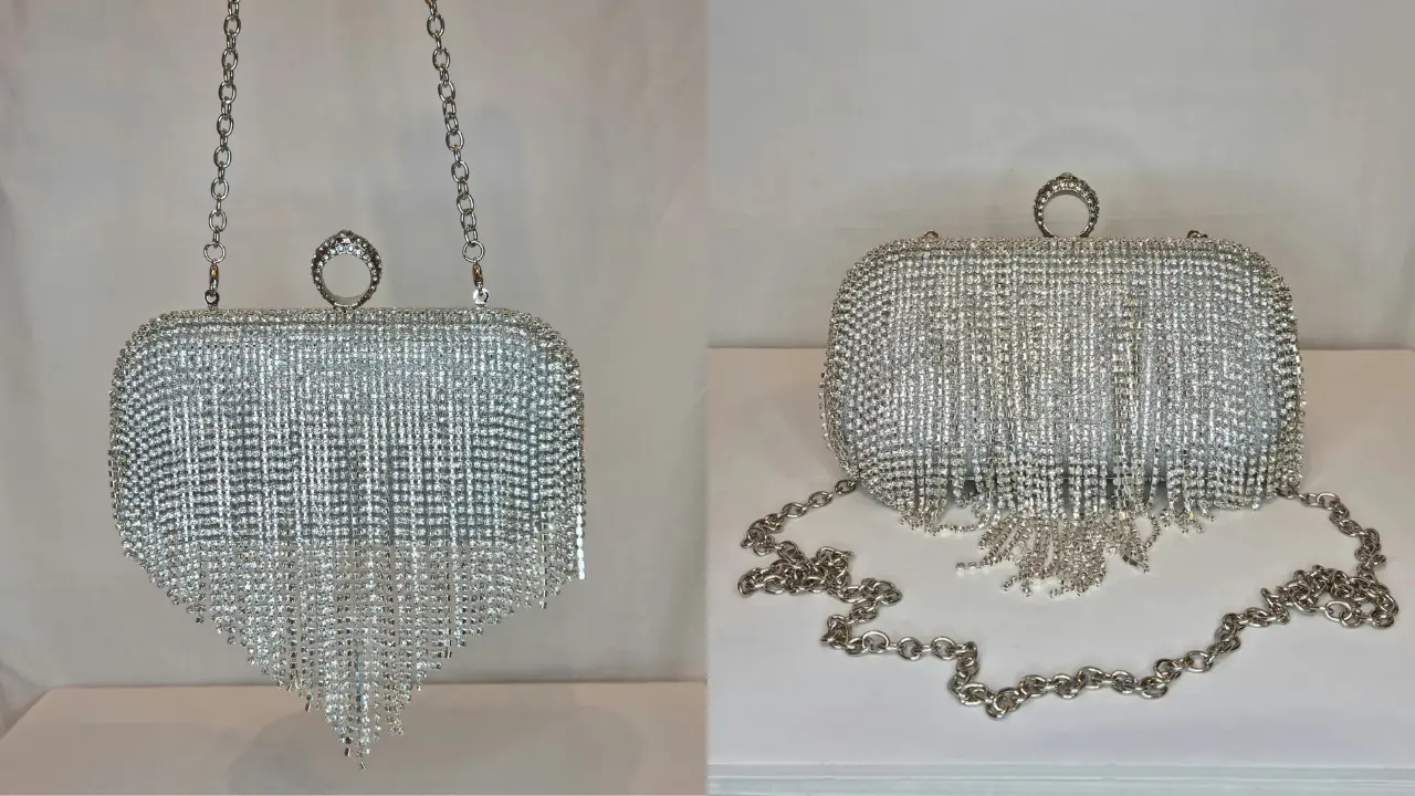 A silver clutch bag covered in sparkling crystals with a chain strap and a fringe detail.