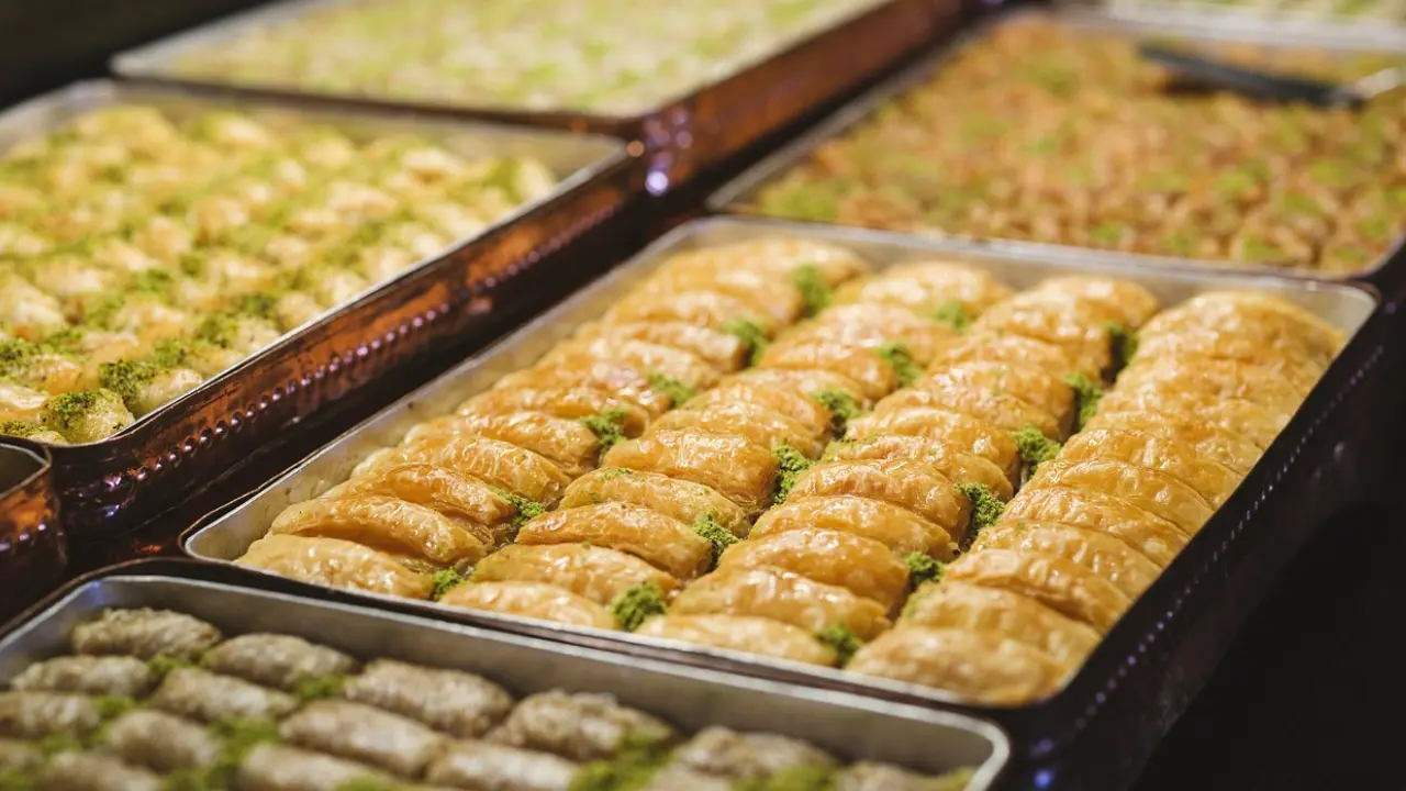 A variety of golden-brown baklava pastries arranged in trays, ready to be served.