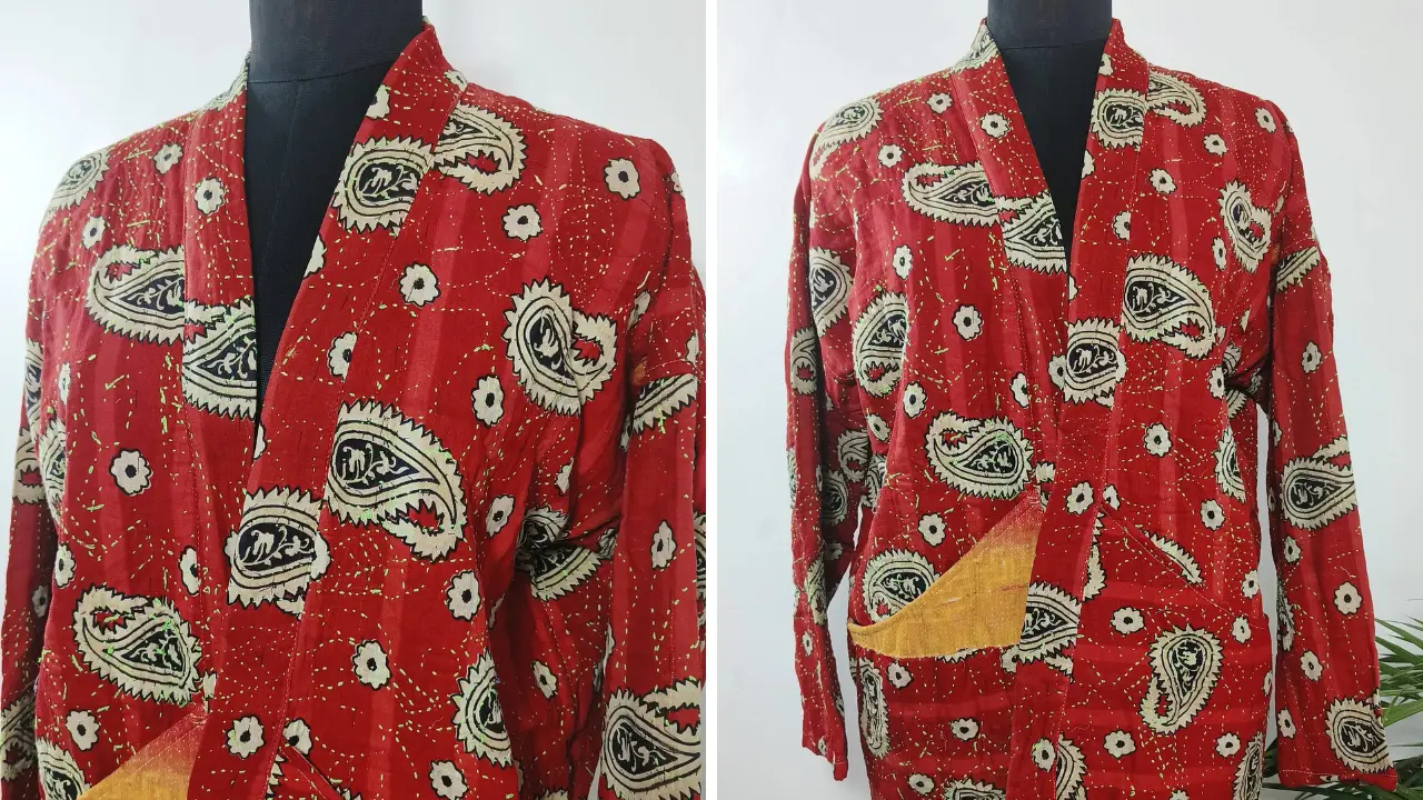 A vintage red kimono with a paisley pattern and long sleeves. The kimono has a V-neckline and is open in the front. The fabric has a worn and faded look, adding to its vintage charm.