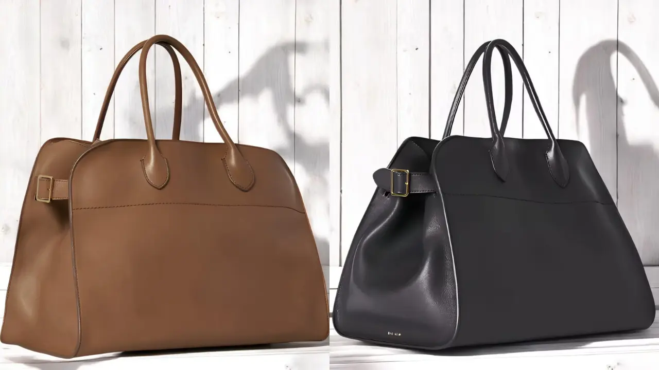 Two large leather tote bags, one brown and one black, with distinctive buckles and handles, displayed against a white wooden background.