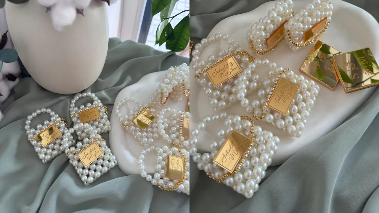 A collection of small pearl-embellished bags with personalized gold name tags, arranged on a white surface with a floral backdrop.