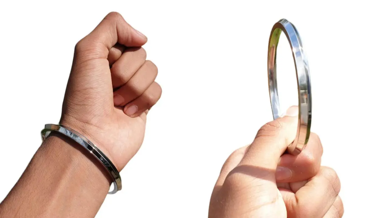 A silver bangle with a grooved design, worn on a person's wrist.