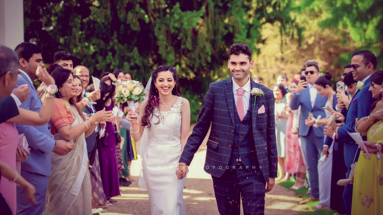 Newlyweds walk through a confetti shower as their guests celebrate their wedding.