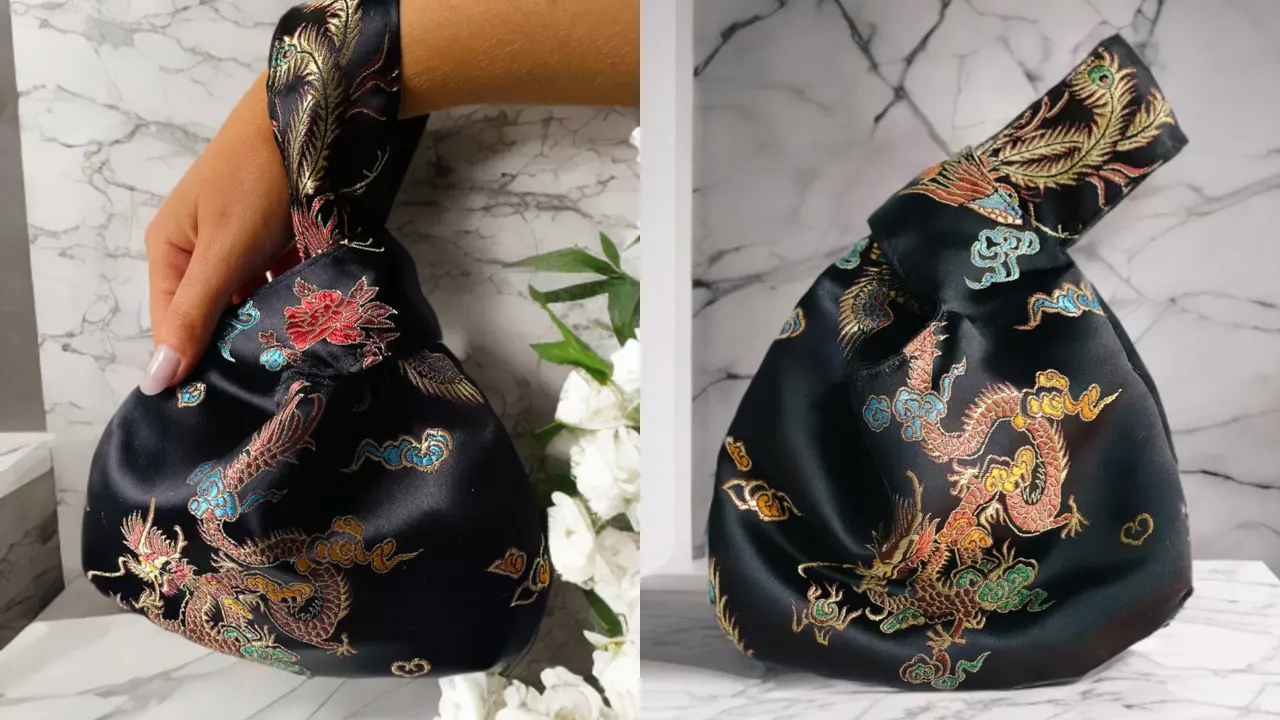 A black satin knot bag with a colorful dragon embroidery, shown from two angles, one with a hand holding the bag.