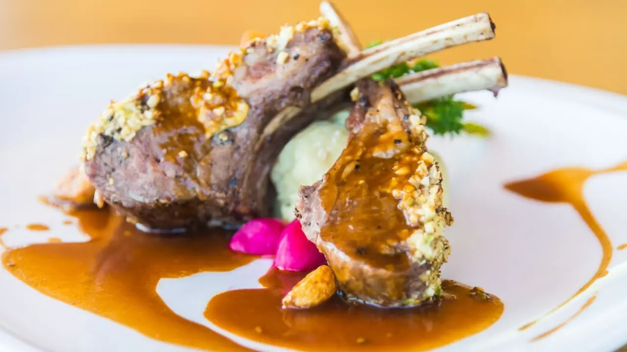 A plate of succulent lamb chops with a crispy crust, served with mashed potatoes and a rich, savory sauce.