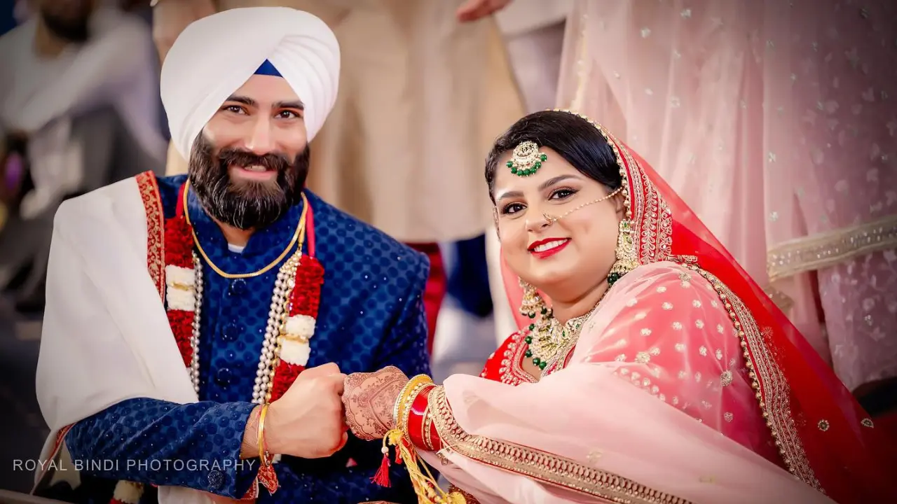 A Sikh bride and groom smiling on their wedding day, adorned in traditional attire with elegant jewellery, showcasing the cultural significance of Sikh wedding rituals.