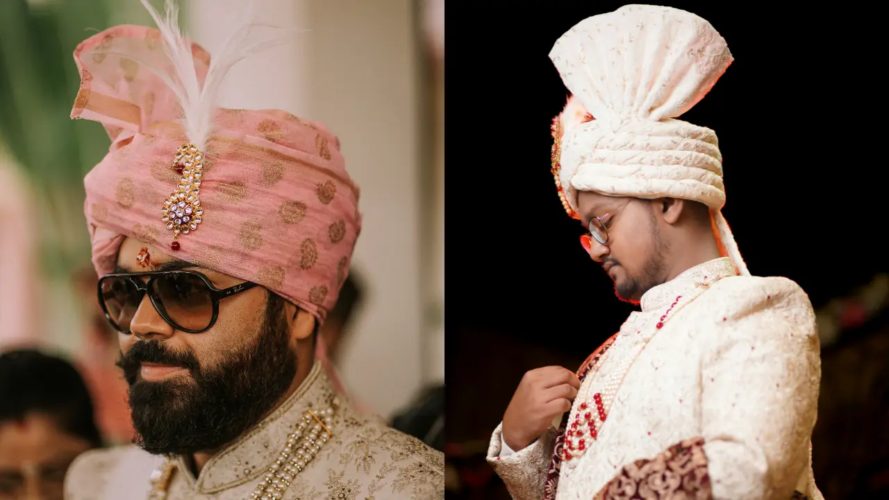 Two Indian men dressed in traditional wedding attire. One is wearing a pink turban with a gold and ruby jewel, and a pearl necklace. The other is wearing a white turban with a red jewel on the front, and a beaded red necklace. Both men are looking down, seemingly in thought.