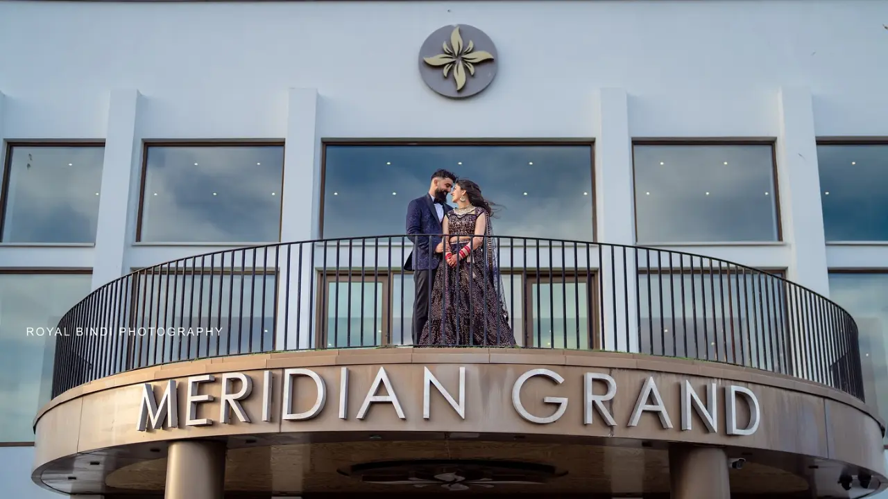 A couple standing on the balcony of the Meridian Grand, gazing at each other, captured by Royal Bindi Photography.